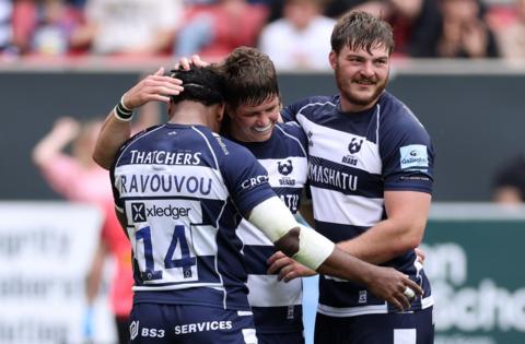 Three Bristol Rugby players celebrate scoring a try against Harlequins at Ashton Gate