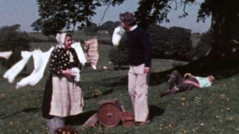 Bernard Falk talking to a woman wearing a bonnet outside, in the Lake District