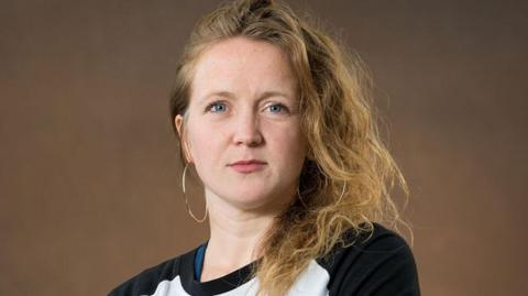 Hollie, wearing a black and white top, smiles at the camera