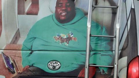 A minibus taxi in Harare with its back painted with a big portrait of Sir Wicknell in a green long-sleeve top with polo players on its front.