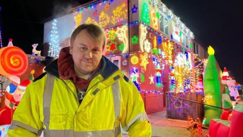 Scott Seare stood in front of his home, which has been thoroughly decorated in Christmas lights.