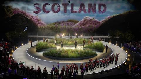 Athletes file past the garden on stage
