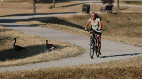A person cycles through parched parkland in Birmingham, Britain, 13 August 2026.