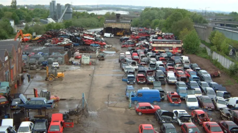 An aerial image of a scrapyard in Derby, with hundreds of cars, a number of buses and crushed vehicles in view