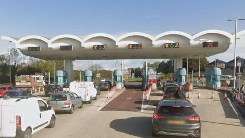 Google Street View image of cars queueing up to use white and blue-coloured toll booths at the Tamar Bridge.