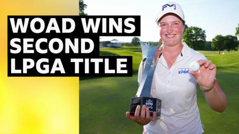 Lottie Woad smiles and holds up a silver trophy Krigor Queen's City Championship trophy in one hand, and a golf ball in her other hand