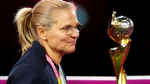 Sarina Wiegman walks past the World Cup trophy in 2023