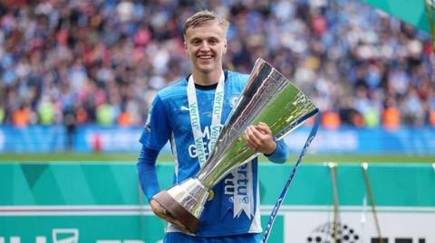 Harley Mills holds the EFL Trophy at Wembley in 2025