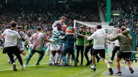 Celtic fans run on the pitch to celebrate a goal against Hearts, sparking a larger pitch invasion.