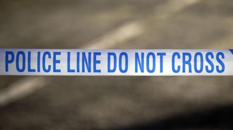 A white tape with the words police line do not cross written in blue.