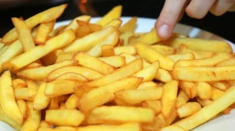Hand picking up a chip from a plate of chips