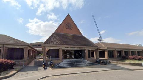 A Google image of Guildford Crown Court. There is a blue sky and a large crane in the background. 