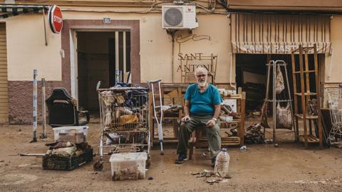  A man sits in front of his house with the belongings he was able to take from his house after catastrophic flash floods due to heavy rain in Sedavi district of Valencia, Spain