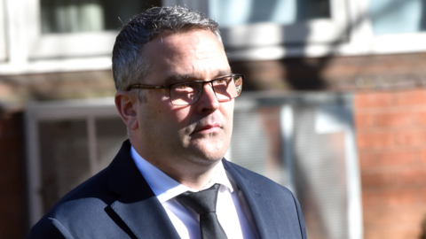 Mark Burrows seen outside court, with short greying hair and wearing a dark blue suit, white shirt and black tie
