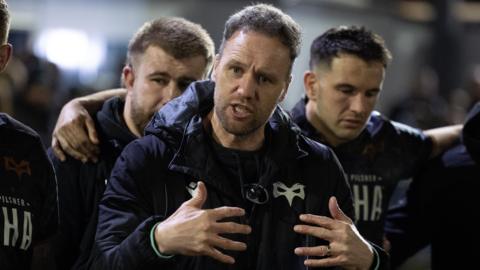 Ospreys head coach Mark Jones gestures with his hands as he talks to his squad in a huddle