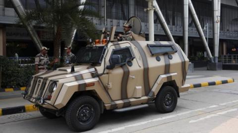 An armed man stands guard on an armoured vehicle outside Sardar Vallabhbhai Patel International (SVPI) airport in Ahmedabad, India