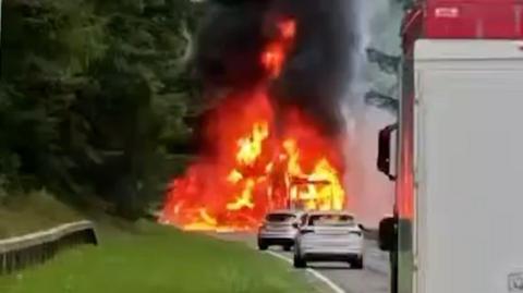 Orange flames in the distance as traffic is queued on the road