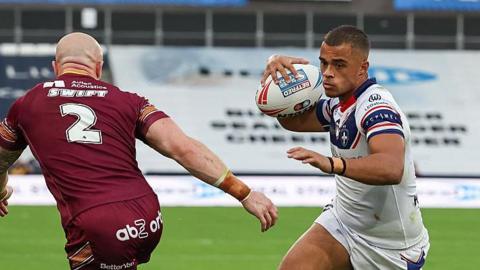 Corey Hall runs with the ball in hand past Huddersfield Giants' Adam Swift