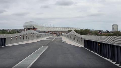 A view of the Stadium of Light from Keel Crossing. It has brick barriers built in an undulating fashion, so they look almost like waves.
