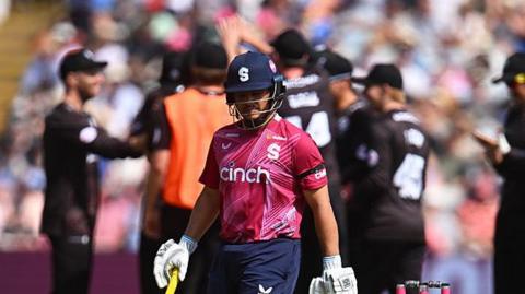 Ricardo Vasconcelos trudging off as Somerset players celebrate in the background