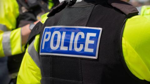 The back of a police officer's jacket. It says police in bold white letters on a blue background. 