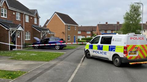 Cordoned off street with police van and damaged car