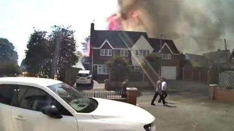 Flames and smoke are rising above a detached house.