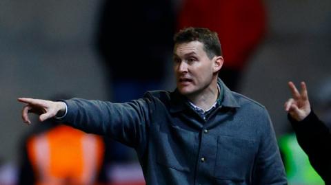 Exeter City boss Matt Taylor pointing to his players from the touchline during a match.
