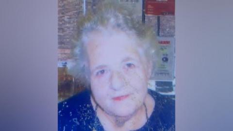 An older lady with grey hair wearing a blue top