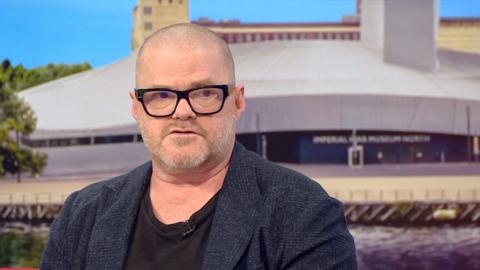 Heston Blumenthal in the BBC Breakfast studio - he wears a blue jacket and black rimmed glasses