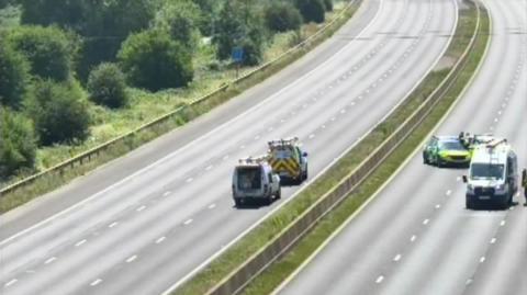 An empty motorway with four cars on it. They are emegency vehicles responding to the power cables fault.