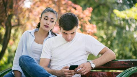 Young woman Spy on Boyfriend Cell Phone - stock photo