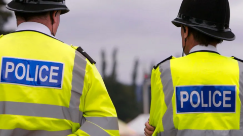 Two police officers - both, middle aged men - with their backs to the camera