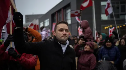 Greenland's Prime Minister Jens-Frederik Nielsen waves a flag during a protest against U.S. President Donald Trump’s demand that the Arctic island be ceded to the U.S., calling for it to be allowed to determine its own future, in Nuuk, Greenland, January 17, 2026