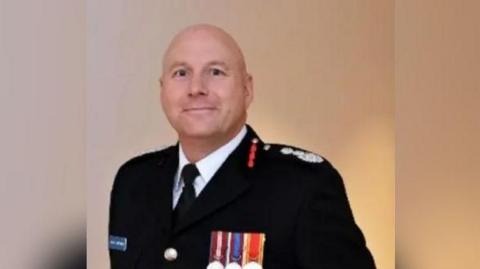 Simon Hardiman in his black fire service uniform with medals on the jacket