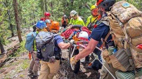 Search and rescue workers carry hiker off mountain