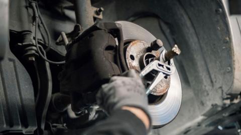 A man in a mask working on a car