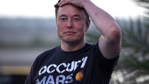 SpaceX founder Elon Musk wears a dark t-shirt with white lettering reading "Occupy Mars" next to a picture of a small red planet