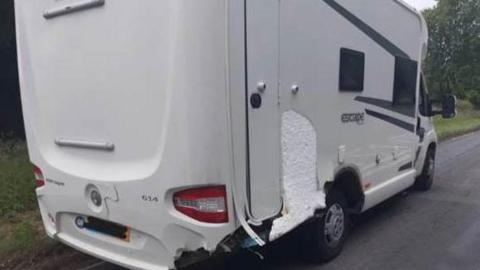 A white motorhome with damage to the back of the vehicle. 