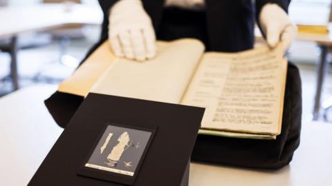 Image of fragments of the Bayeux tapestry displayed behind a black cloth.