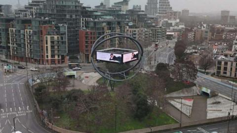 Current advertising structure shows screen in orb on roundabout with cars, bus and lorry