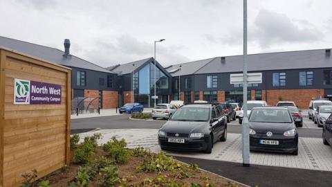 A view of the North West Community Campus in Dumfries a brick building with cars parked outside