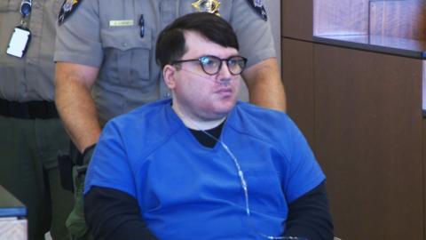 Nicholas Ross is brought into the Utah courtroom in a wheelchair. He is wearing a blue prison uniform and has an oxygen tube connected to his nose