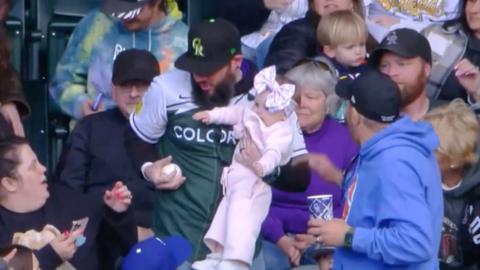 Man holding a baby catches a baseball