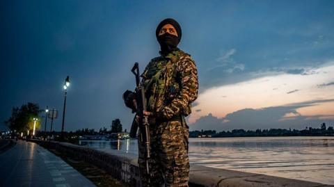 A paramilitary soldier stands guard on the bank of Srinagar's Dal lake on 10 May in Indian-administered Kashmir. Both India and Pakistan have ceased hostilities since they announced the ceasefire but say they remain vigilant. 