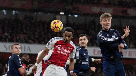 Jurrien Timber opens the scoring for Arsenal. He is heading the ball while Manchester United players are nearby.