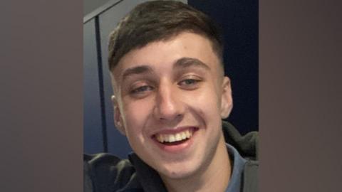 A photograph of Jay Slater, in close-up. He is smiling at the camera