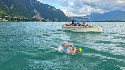 Neil Gilson swimming in Lake Geneva with a support boat nearby him