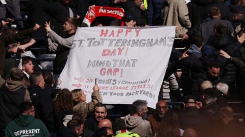 Arsenal fans holding a St Totteringham's Day flag