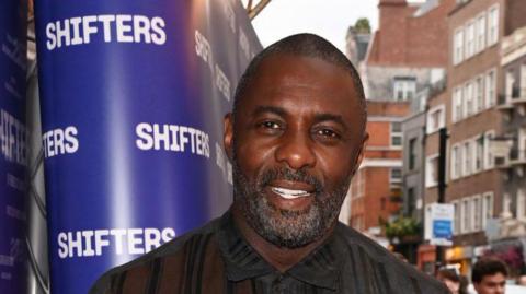 Idris Elba  outside the Shifters theatre wearing a black shirt